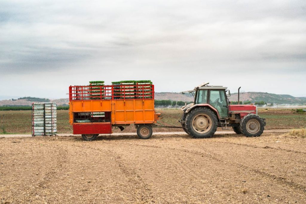 Un tracteur travaillant avec une remorque en réhausse grillagée
