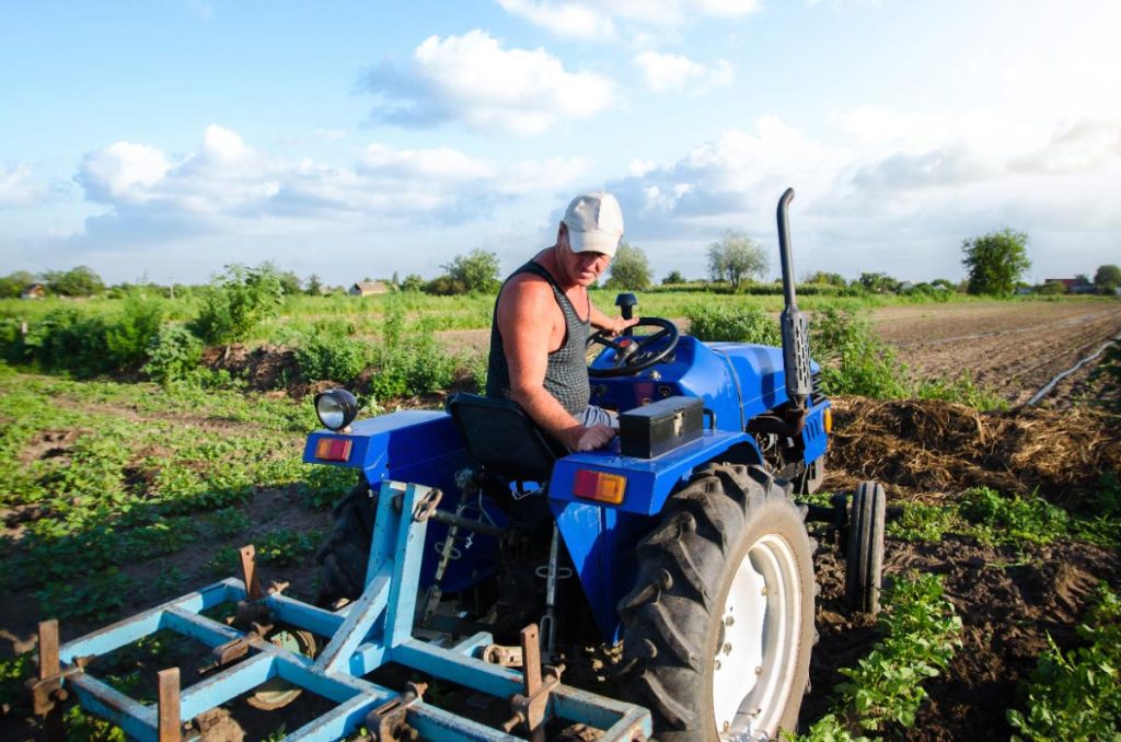 Un homme qui travaille sur un champ avec un quad et une herse