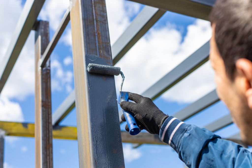 Un ouvrier qui peint une structure métallique