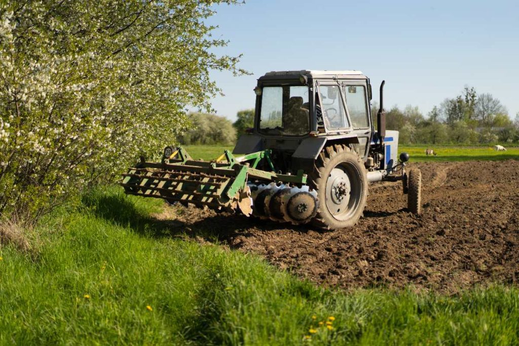 Un quad sur un champ agricole avec une herse