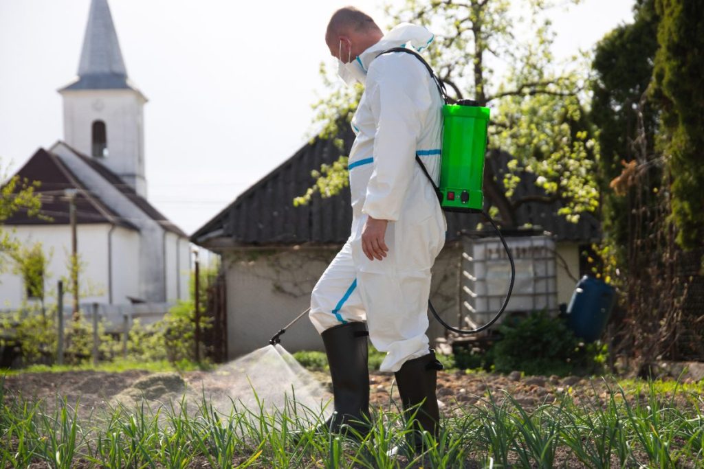 Un agricluteur en combinaisant pulvérisant ses cultures