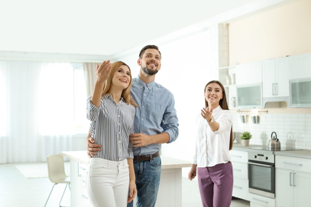 Un agent immobilier montrant une nouvelle maison au jeune couple