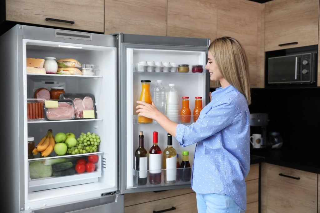 Une femme choisissant des nourritures dans le frigo