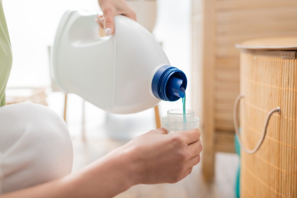 Une femme qui verse de l'eau de javel dans un petit contenant