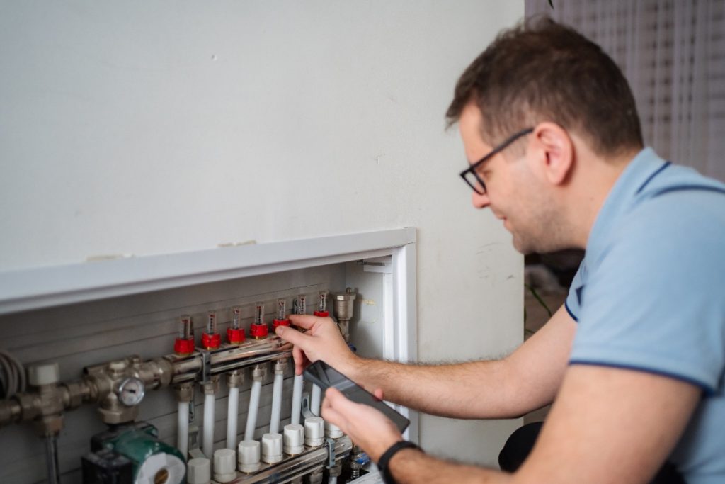 Un homme inspectant le collecteur de chauffage au sol