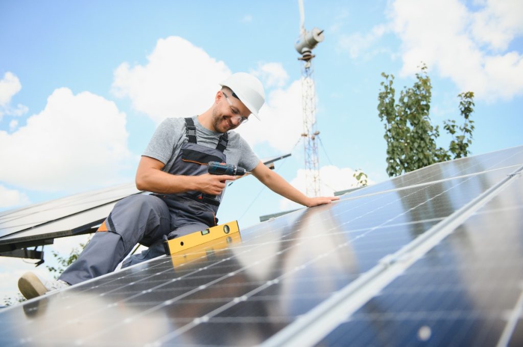 Un homme qui installe un panneau solaire