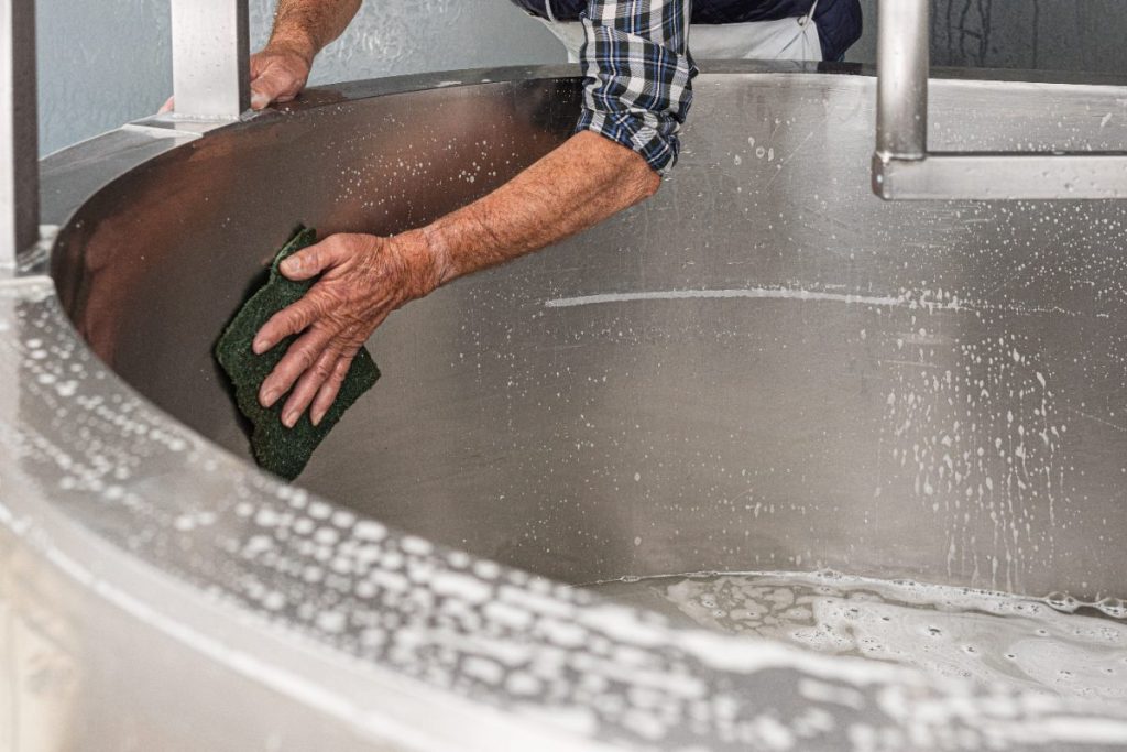 Un homme nettoyant un réservoir acier inox