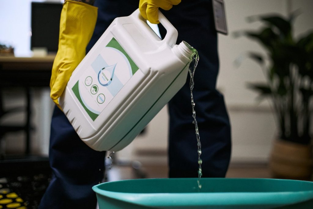 Un homme versant de l'eau de javel dans un sceau