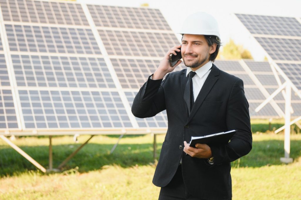 Un ingénieur au téléphone devant des panneaux solaires