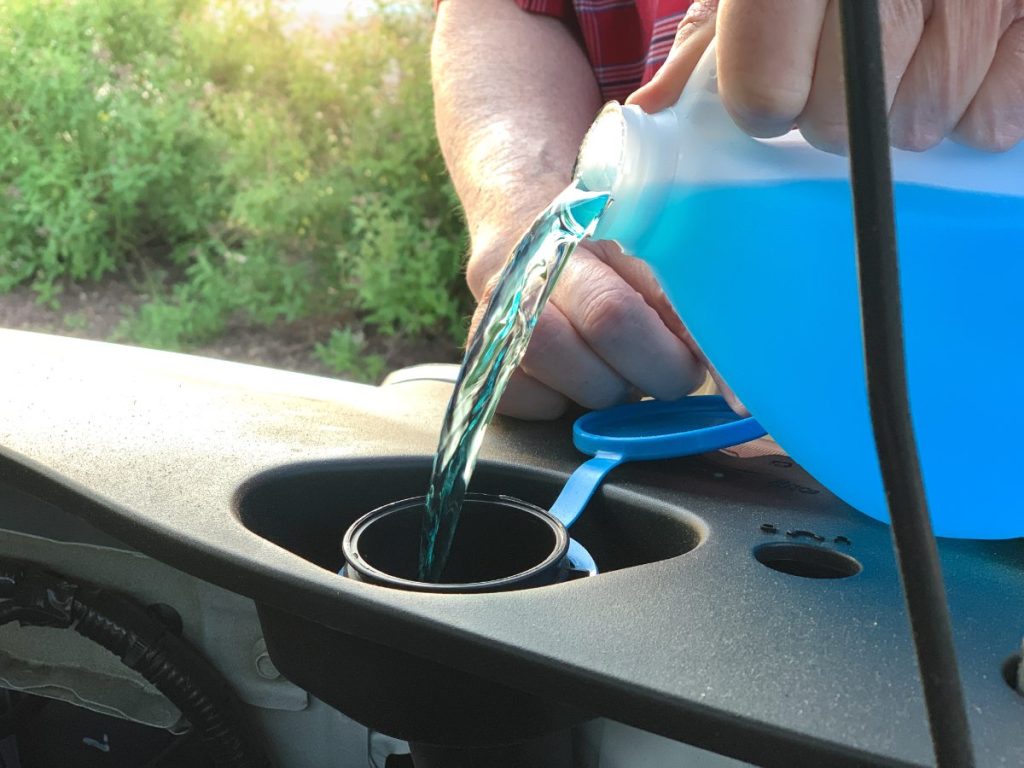 Une personne qui verse de l'eau de javel dans un récipient