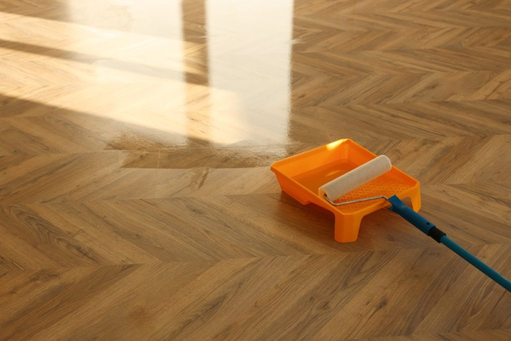 Un rouleau de peinture sur le parquet en bois