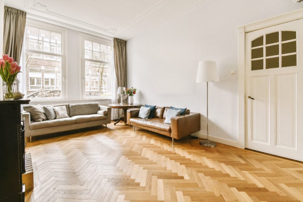 Un sol en parquet lumineux et des canapés placés près de la fenêtre