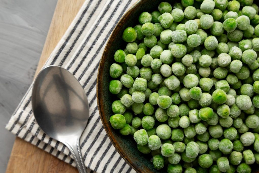 Un bol remplid e petit pois avec une cuillère sur la table