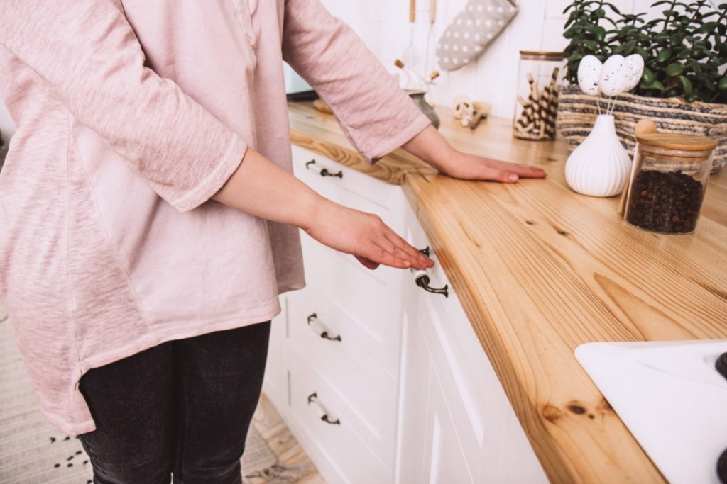 Une femme qui ferme le placard de cuisine