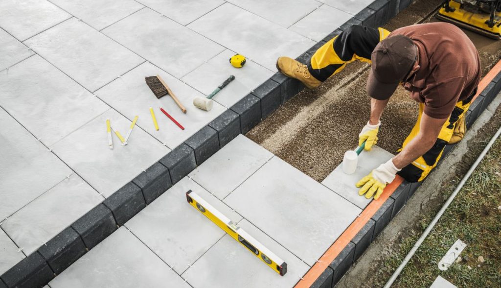 Un ouvrier réalisant une pose de dalle sur une terrasse
