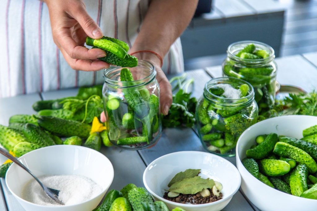 Une personne mettant des cornichons dans un bocal