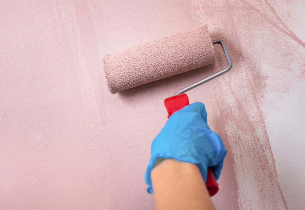 Une personne qui peint le mur avec rouleau