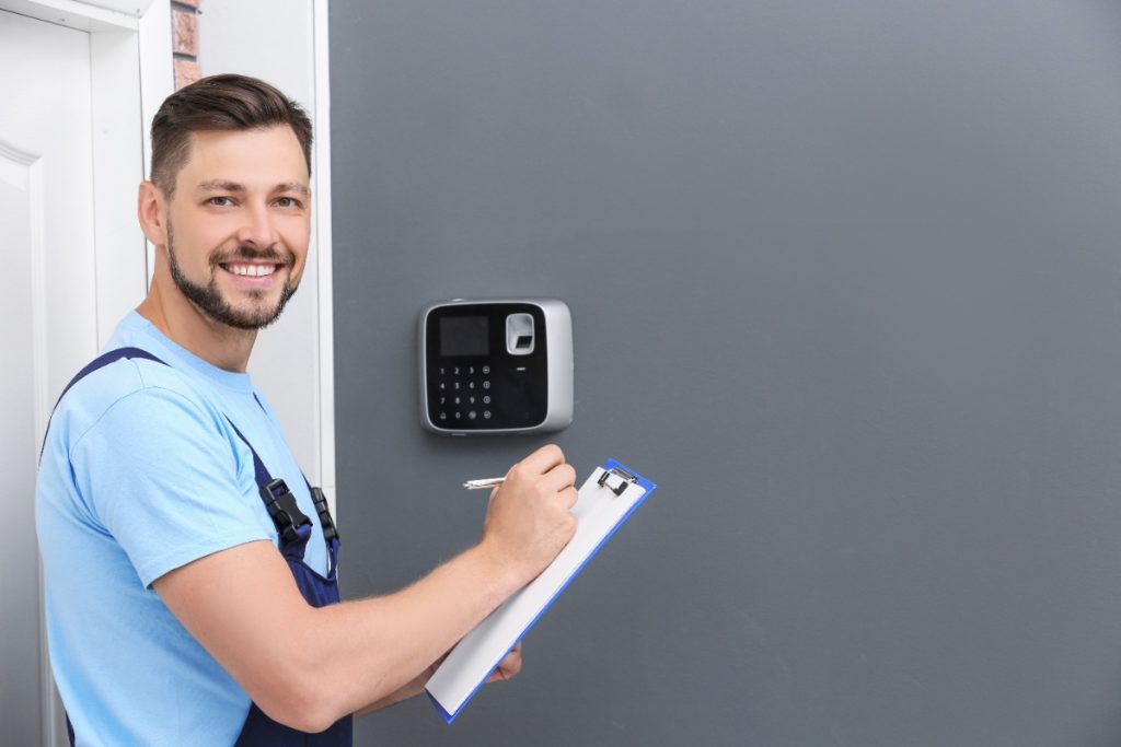 Un serrurier installant un système de sécurité sur le mur