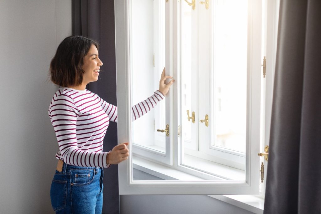Une femme souriante ouvrant la fenêtre