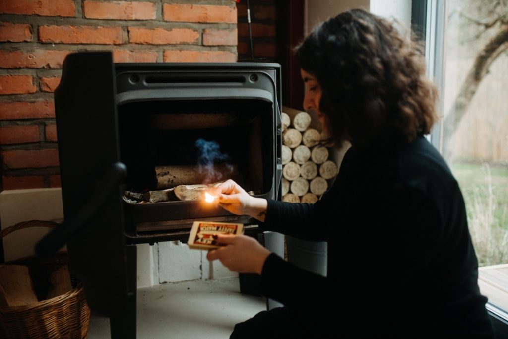 Une femme allumant le feu  d la poêle avec une bougie d'allumage